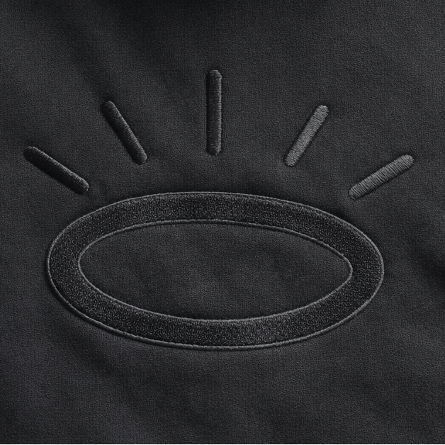 Close-up of black-on-black Tatami halo embroidery on jet black hoodie, showing flat woven stitching with subtle sheen.